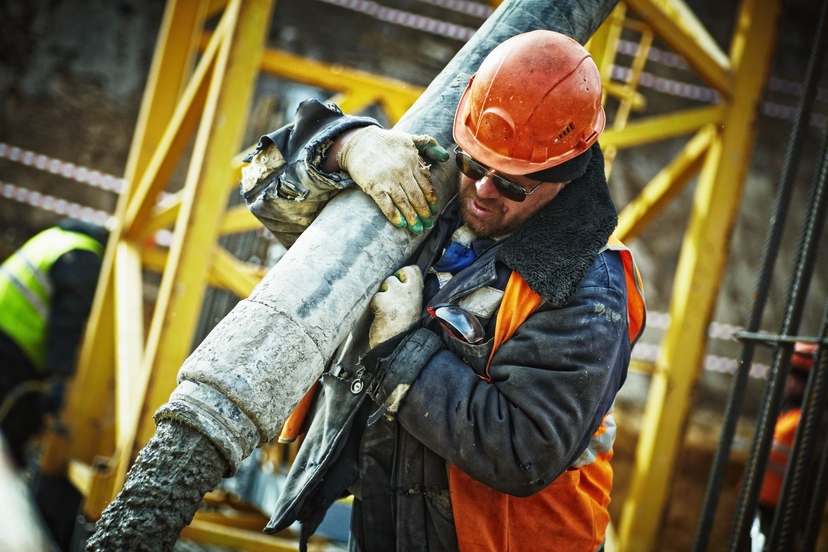 A construction worker guiding a concrete pump hose on site